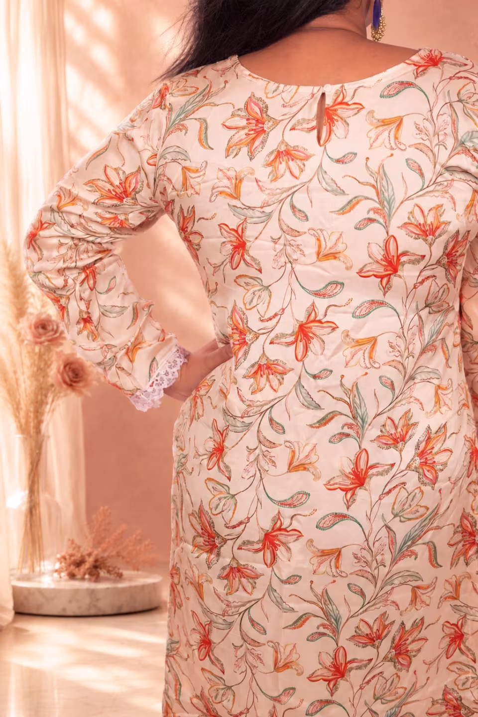 Back view of a woman wearing a cream floral silk kurti featuring a teardrop keyhole neck design and floral print.