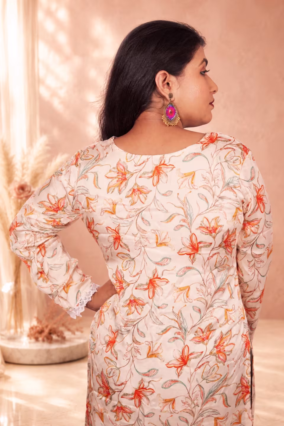 Back view of a woman showcasing the elegant fit and peach floral print of a cream floral silk kurti.