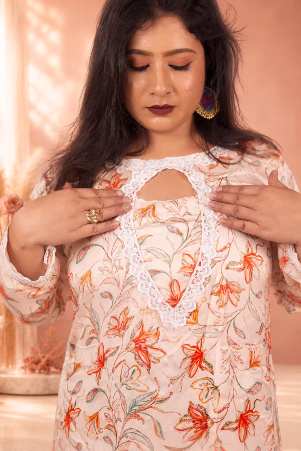A close-up view of the intricate white lace keyhole neckline on a cream floral silk kurti.