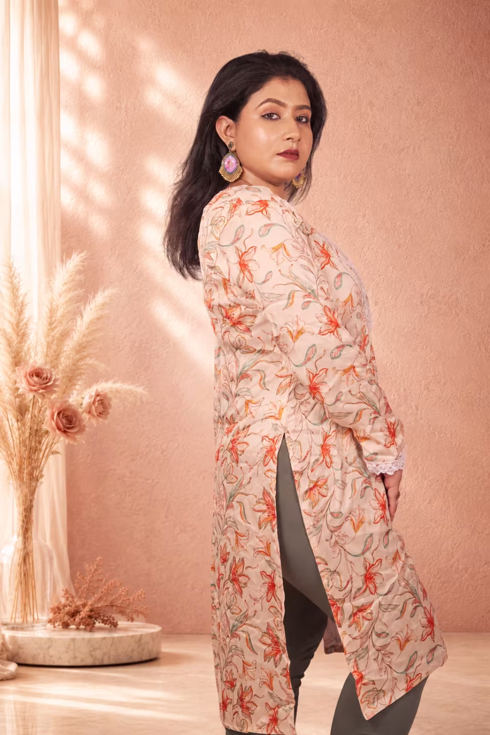 Close-up of a woman showcasing the peach floral print and lace sleeve design of a cream floral silk kurti.