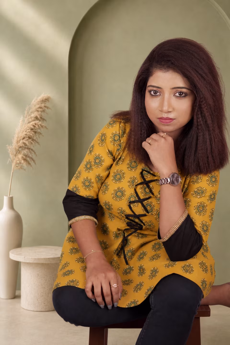 Mustard yellow Bagru block print A-line kurti with black contrast sleeve and lace-up front — seated front view