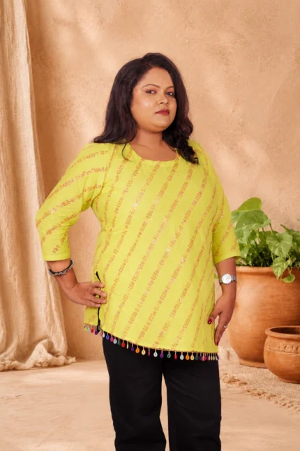 Front view of lime green cotton kurti with sequin stripe print, hands on hips, black pants