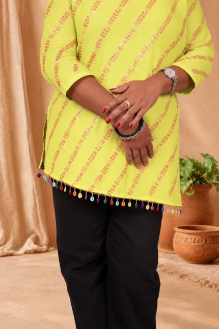 Close-up of lime green kurti tassel hem with colorful shell beads and hand detail